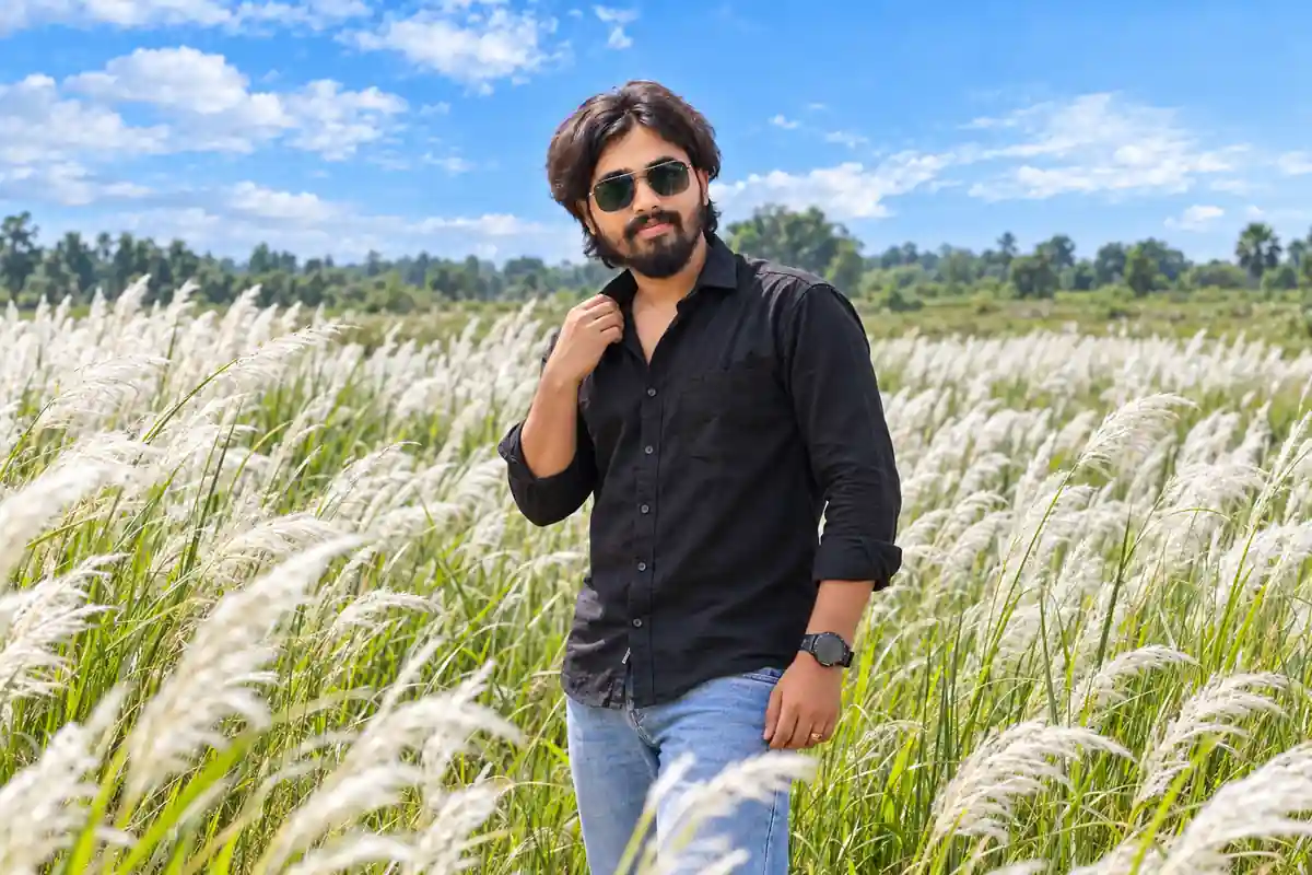 Young man in black shirt and blue jeans standing in a white Kash flower field